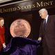 Fore and an assistant unveil the Kent County penny, which boasts a nod to the cinder-block factory.